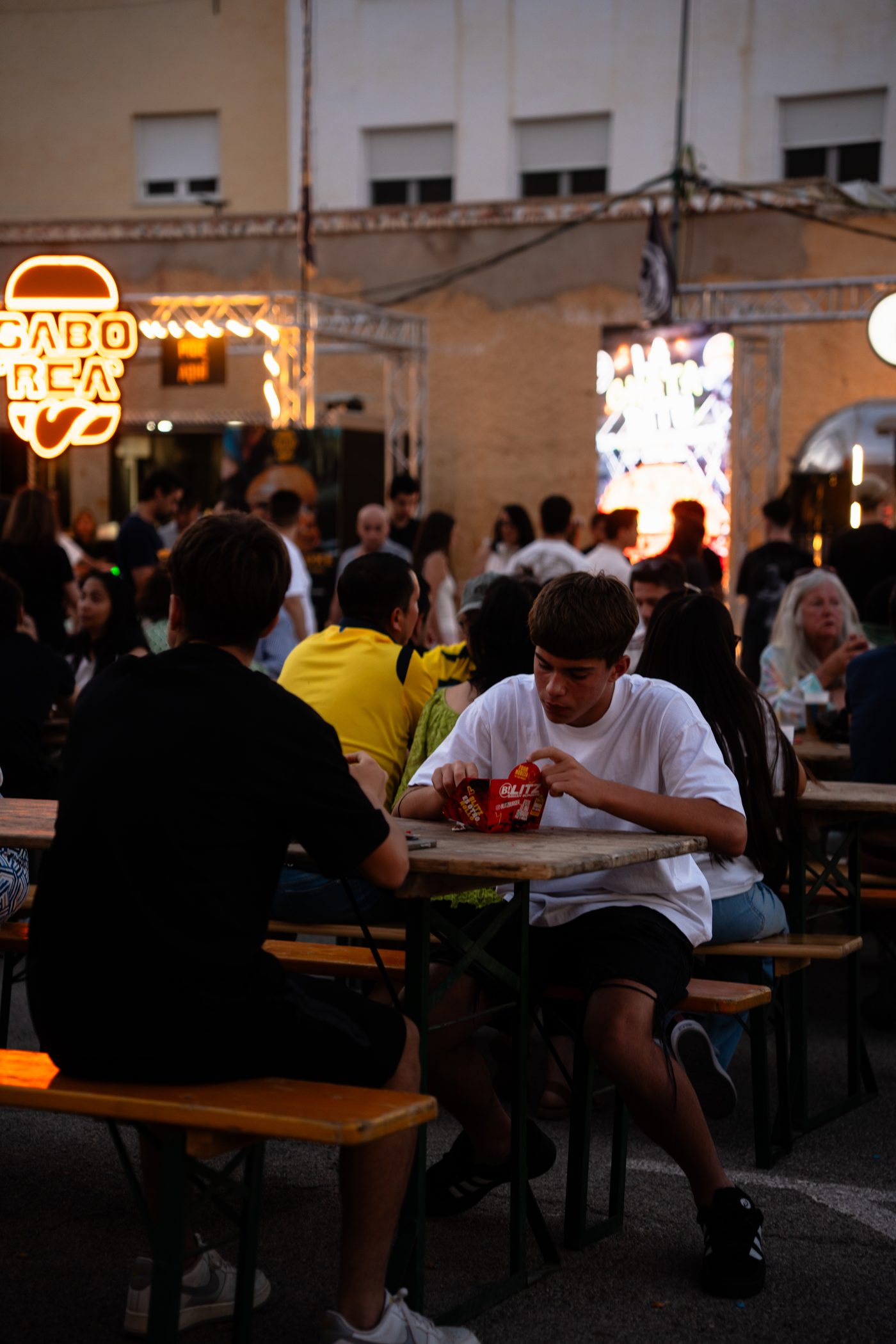 Público en las mesas del festival, con el rótulo luminoso de un food truck al fondo